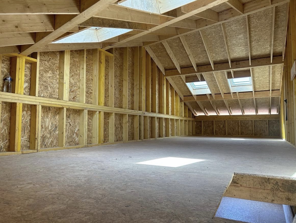 Aménagement de combles avec charpente bois, panneaux OSB et fenêtres de toit lumineuses.