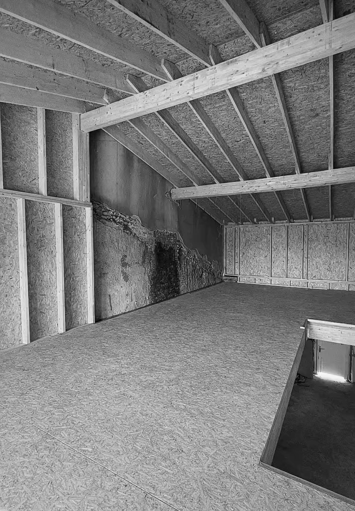Combles en chantier avec plancher OSB et charpente bois apparente.