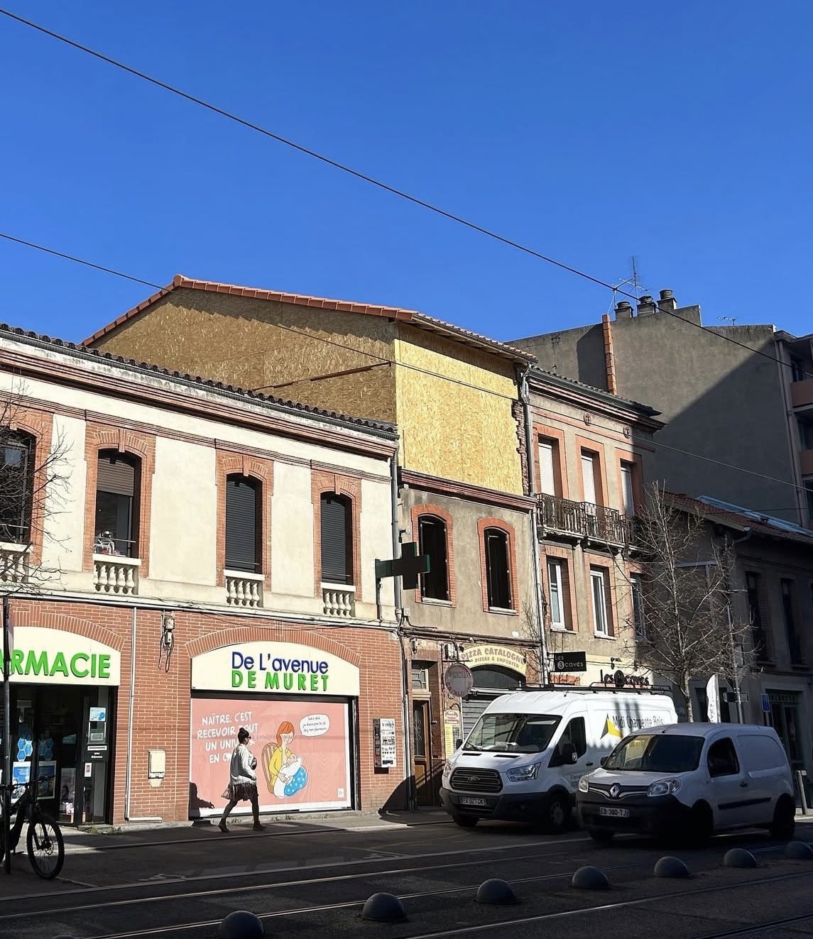 Pharmacie De l'avenue DE MURET et bâtiment en travaux à Toulouse avec vans garés sous un ciel bleu.