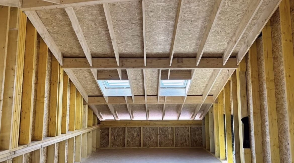 Charpente bois intérieure avec panneaux OSB et deux fenêtres de toit.
