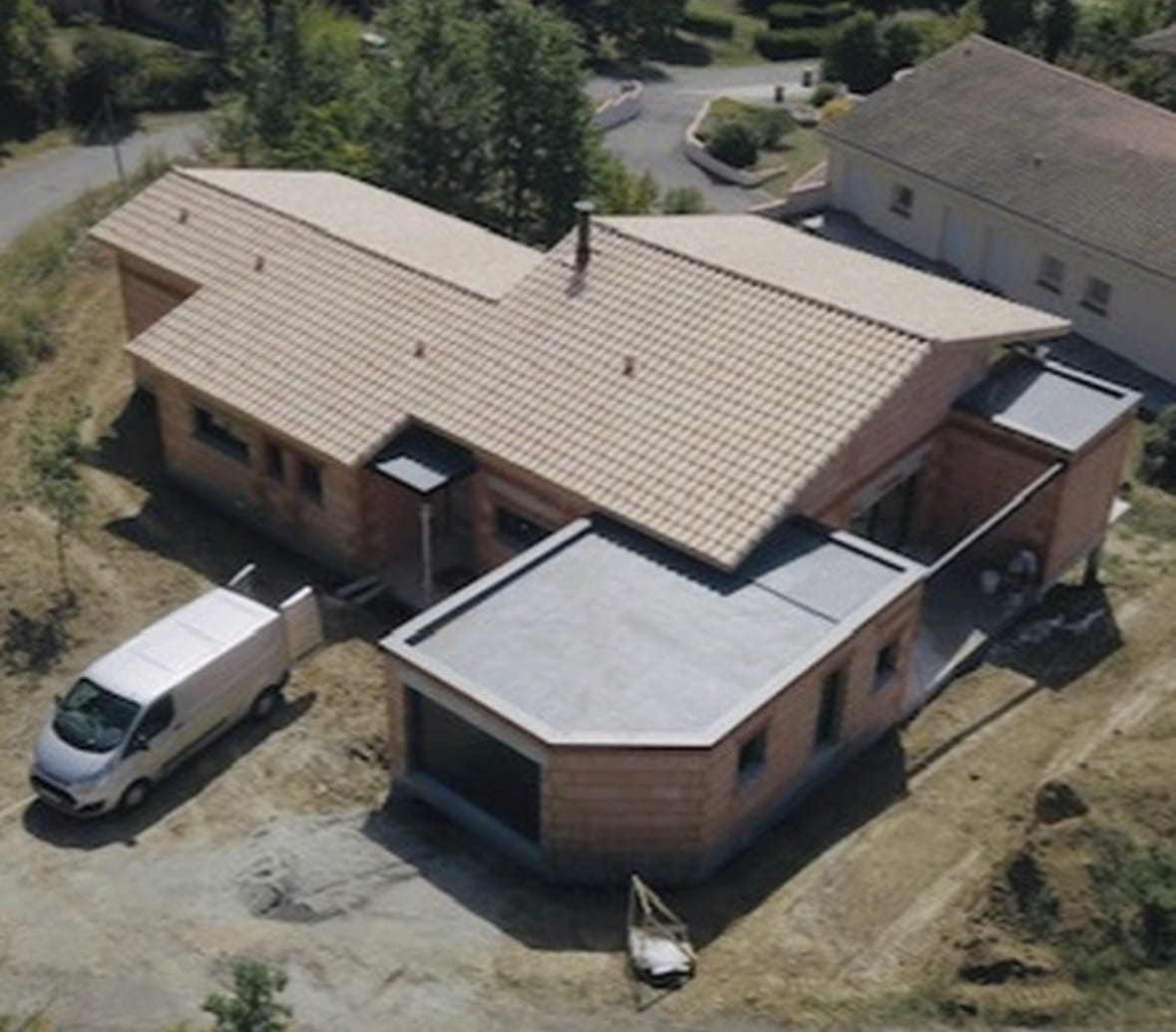 Maison en briques rouges, toiture tuiles et toit plat, vue aérienne avec fourgonnette blanche.
