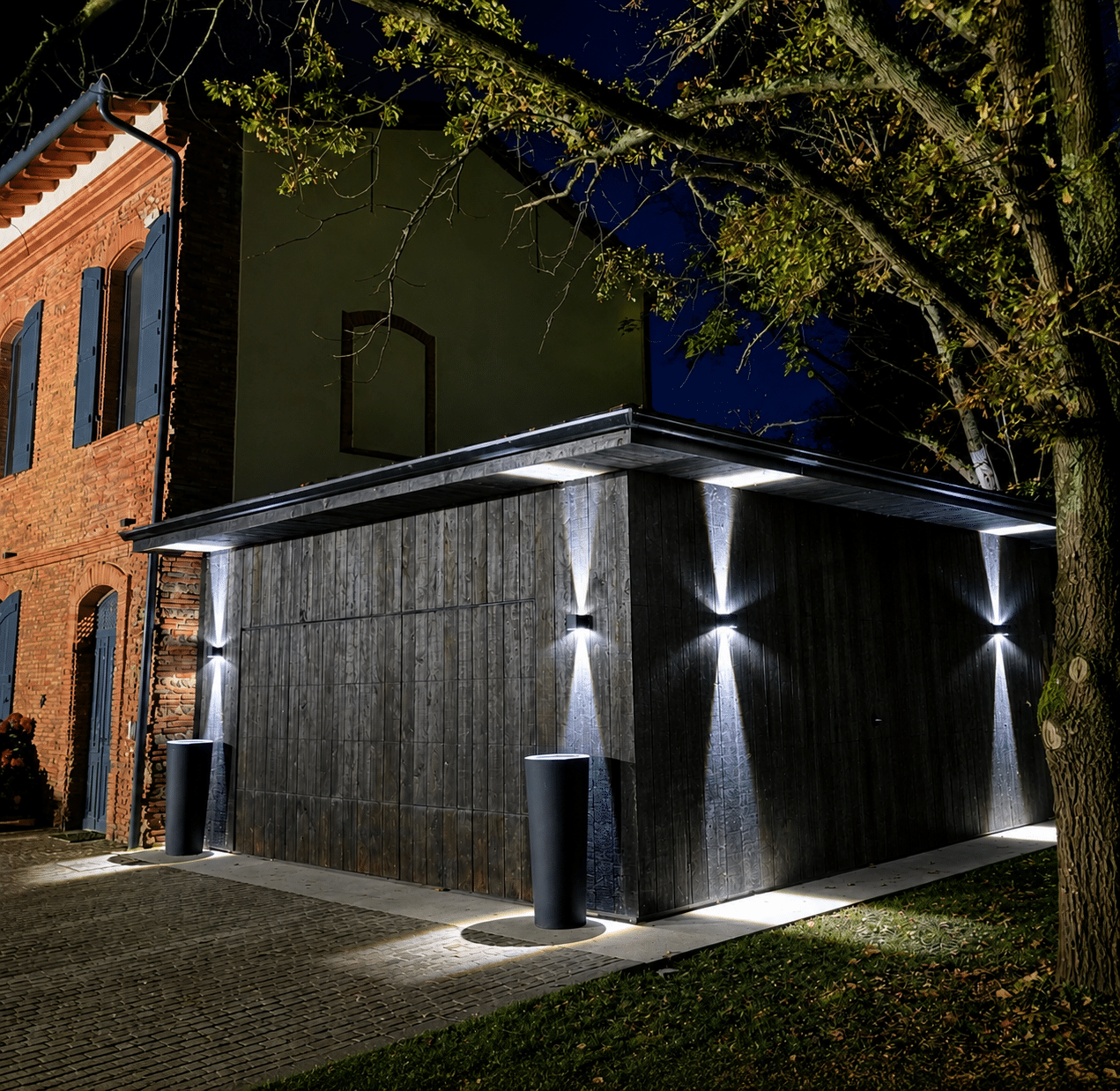 Garage moderne en bois noir avec éclairage mural design bidirectionnel créant des faisceaux lumineux.