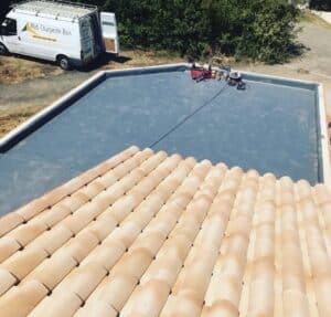 Toit plat en membrane grise, camionnette Midi Charpente Bois et tuiles.