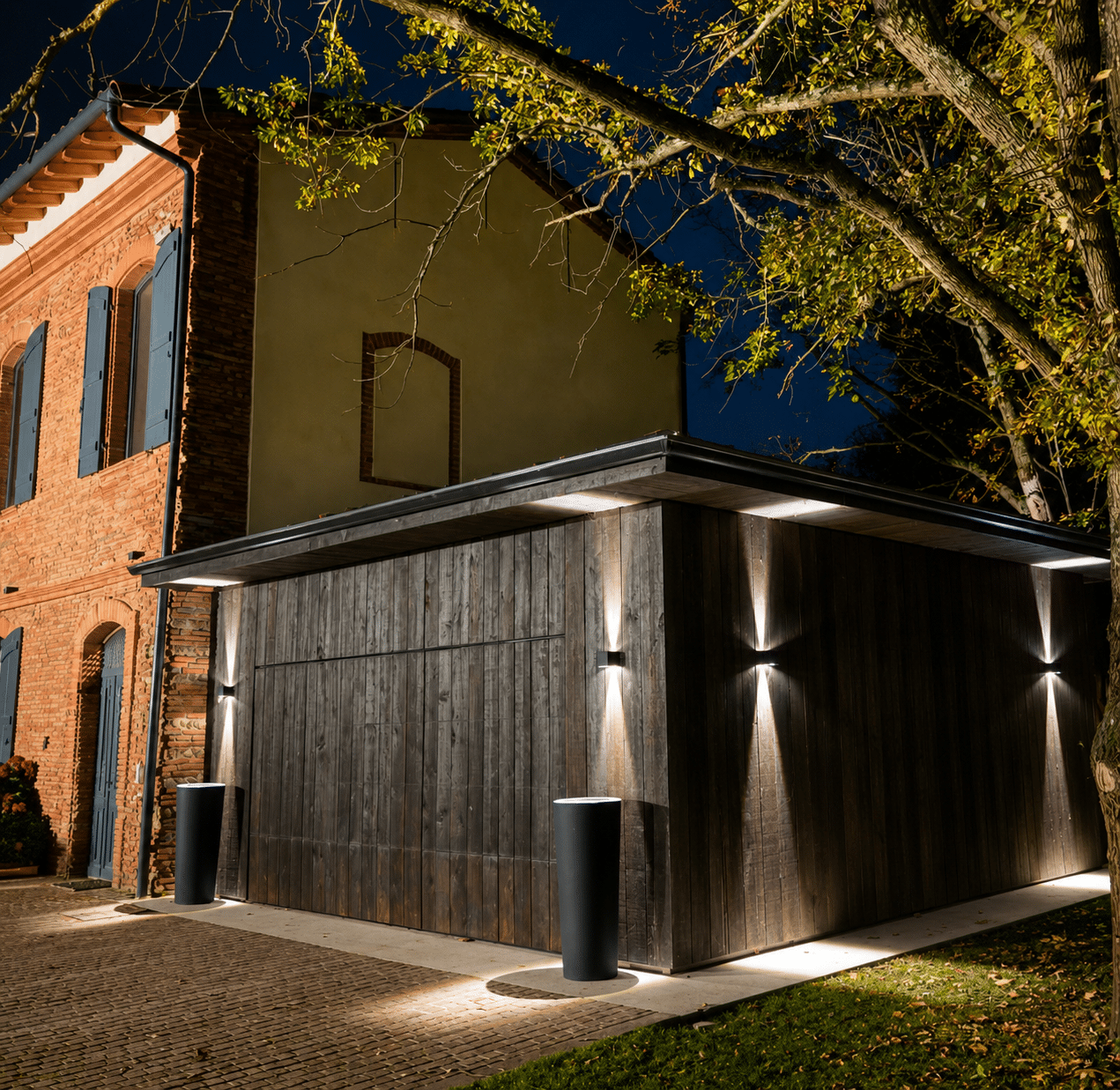 Garage bois moderne avec éclairage extérieur design de nuit devant maison en briques.