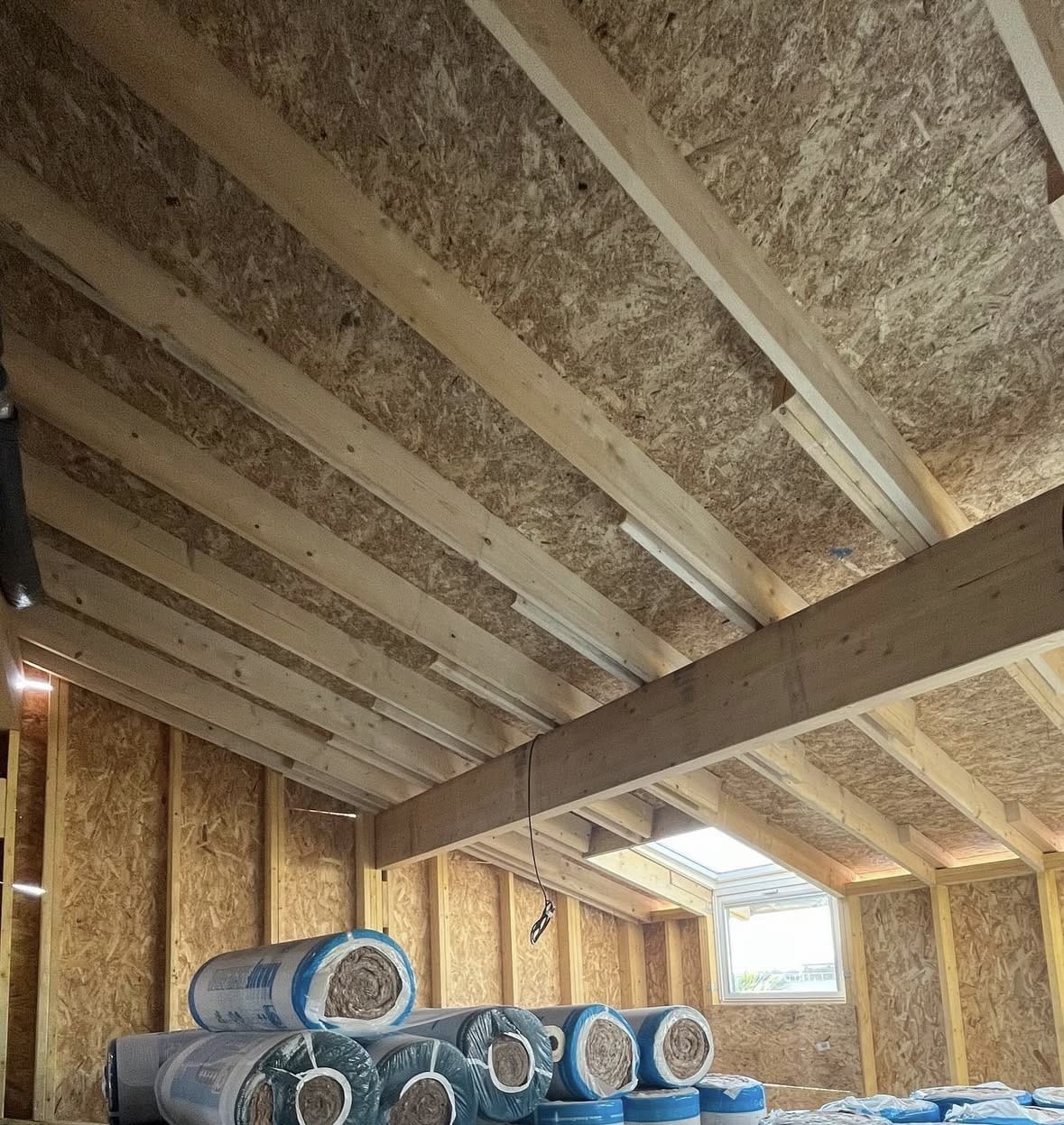 Charpente bois, panneaux OSB et rouleaux d'isolation Knauf dans un comble en travaux.