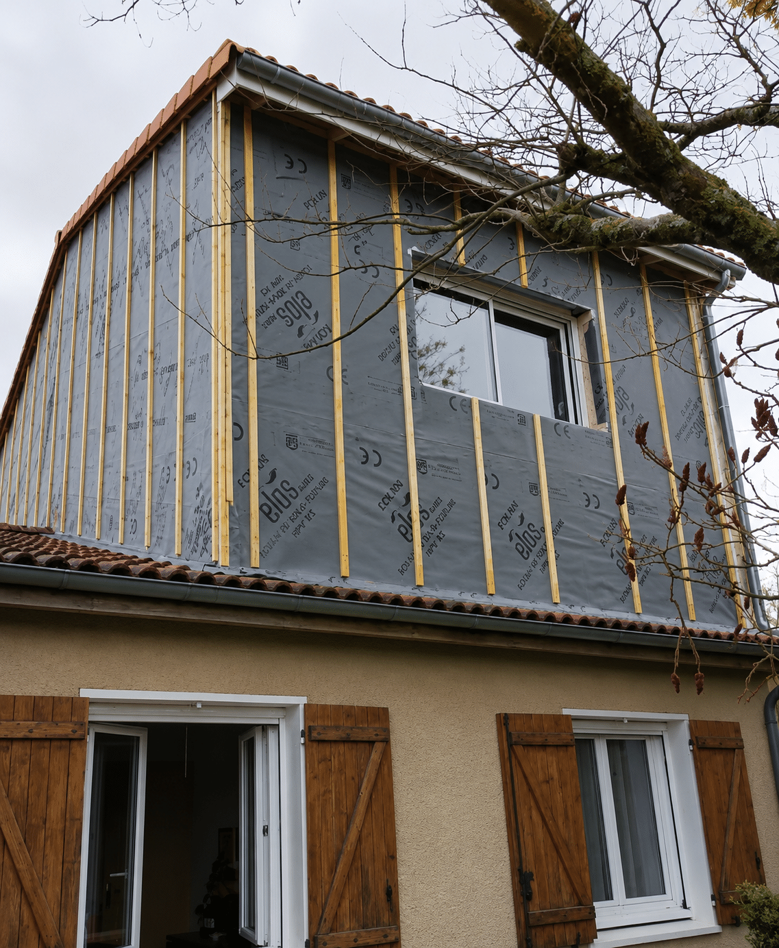 Maison en rénovation : membrane grise ELOS et liteaux de bois verticaux.