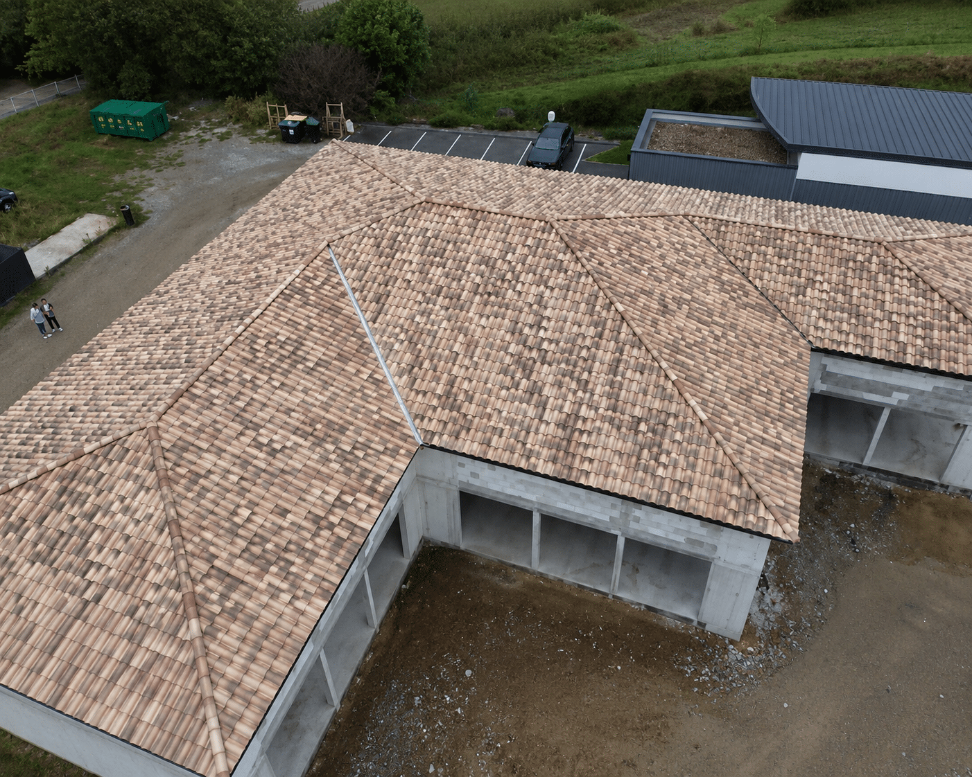 Toiture en tuiles romanes sur une structure en béton en construction, vue de dessus d'un chantier moderne.