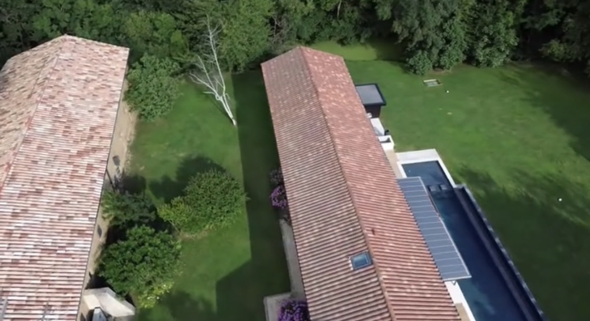 Vue aérienne de villa moderne avec piscine, toits en tuiles et jardin arboré.